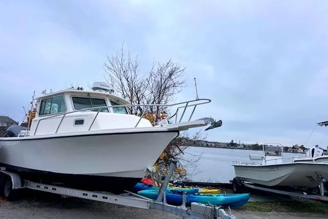 Slide: The Image of 2005 Parker 2320 SL Sport Cabin boat on trailer by waterfront, with kayaks nearby. - 4