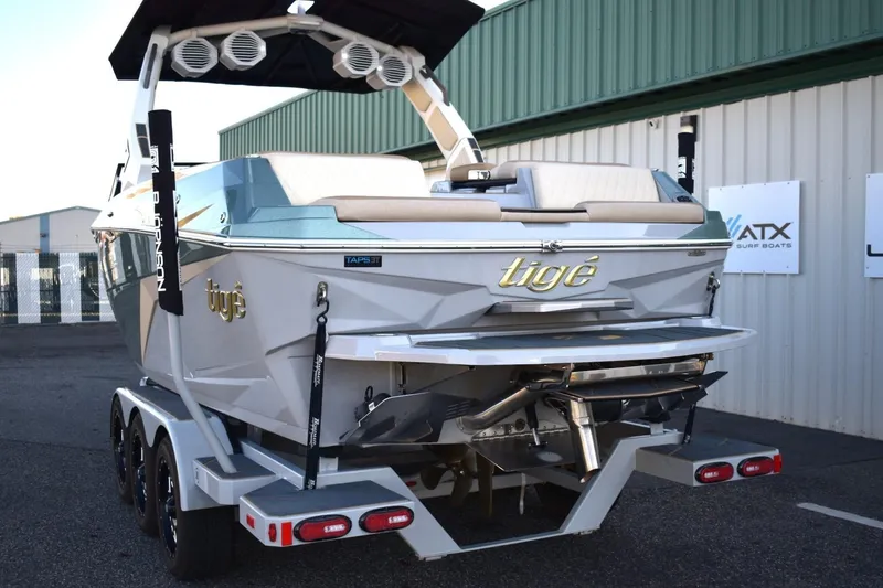 Slide: The Image of 2026 Tigé Z3 boat on trailer, rear view, parked near green building. - 12