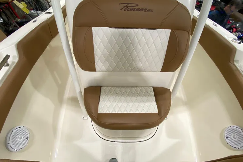 Slide: The Image of 2024 Pioneer 202 Islander boat interior with tan seating and sturdy framework in a warehouse. - 10