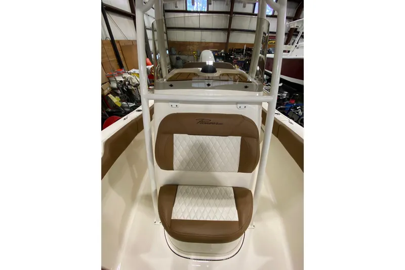 Slide: The Image of 2024 Pioneer 202 Islander boat interior with brown cushioned seating in a workshop setting. - 16