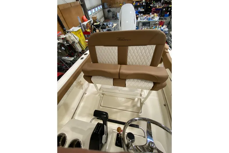 Slide: The Image of 2024 Pioneer 202 Islander boat with tan seating in a spacious indoor facility. - 17