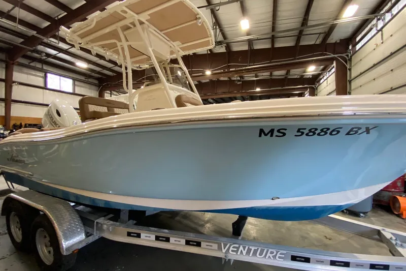 Slide: The Image of 2024 Pioneer 202 Islander boat with Suzuki engine in a garage setting. - 2