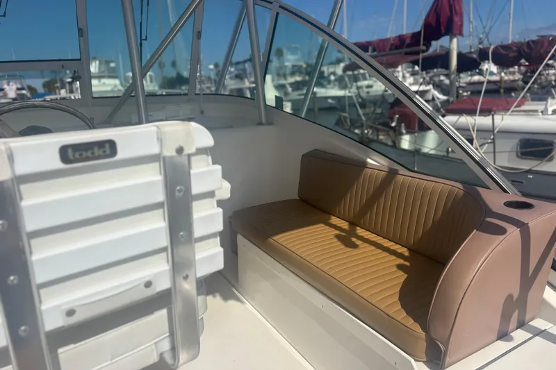 Slide: The Image of 2004 Luhrs 32 Open boat interior with tan seating and marina background. - 16