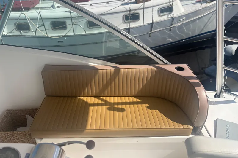 Slide: The Image of 2004 Luhrs 32 Open boat with tan cushioned seating and cup holder, docked near other boats. - 17