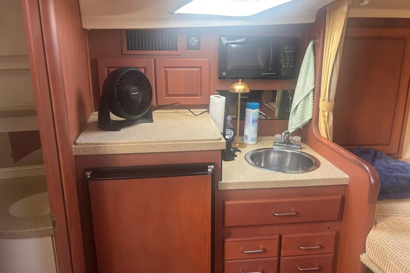 Slide: The Image of 2004 Luhrs 32 Open cabin kitchen with sink, microwave, and fan. - 28