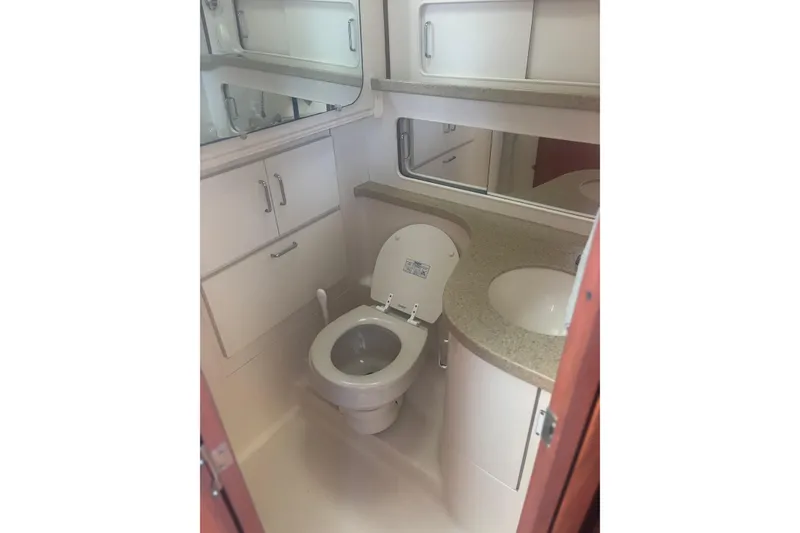 Slide: The Image of 2004 Luhrs 32 Open boat bathroom with toilet, sink, and storage cabinets. - 29