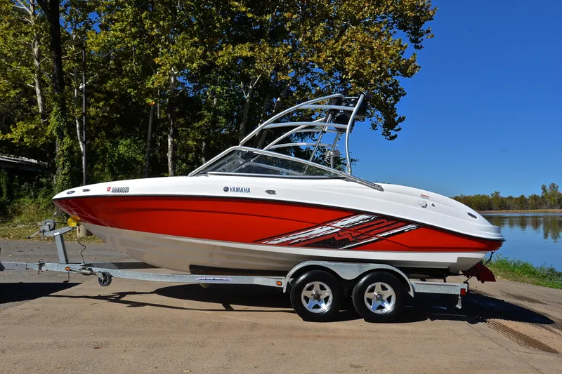 Slide: The Image of 2008 Yamaha AR210 boat on trailer, red and white design, parked near a lake. - 12