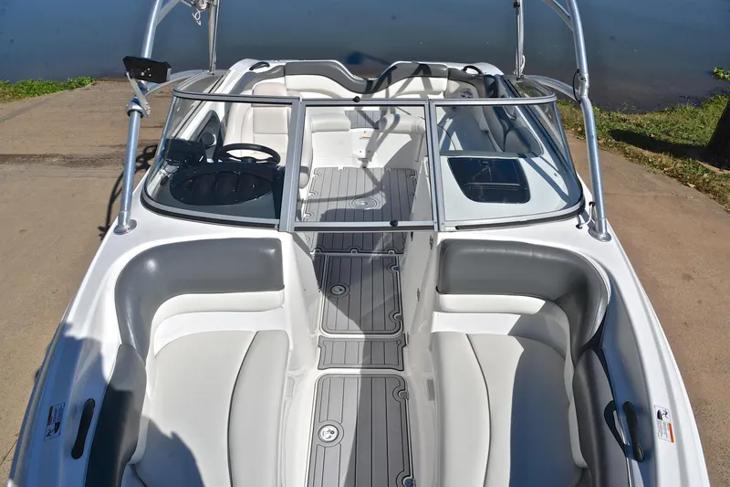 Slide: The Image of 2008 Yamaha Boats AR210 interior with seating and steering, docked by the water. - 21
