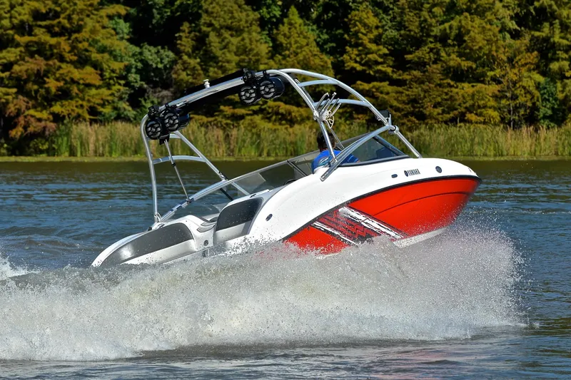 Slide: The Image of 2008 Yamaha AR210 boat speeding on a lake with lush green trees in the background. - 5