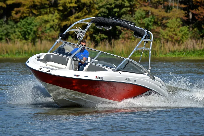 Slide: The Image of 2008 Yamaha AR210 boat cruising on a lake with lush green background. - 8