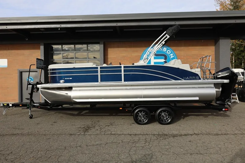 The Image of 2026 Harris CRUISER 230 SL pontoon boat on trailer, parked outside a building. - 1