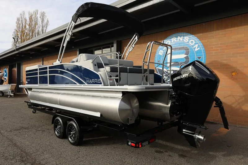 Slide: The Image of 2026 Harris CRUISER 230 SL pontoon boat with Mercury engine on trailer, parked outdoors. - 3