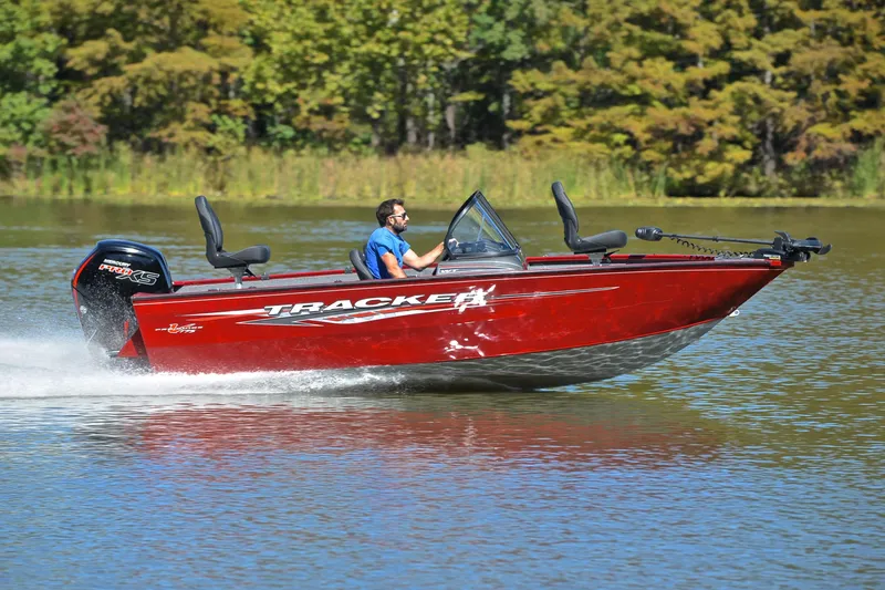 Slide: The Image of 2022 Bass Tracker Pro Guide V175 WT boat cruising on a lake with lush green background. - 3