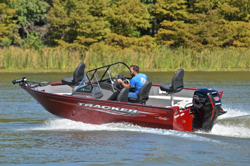 Slide: The Image of 2022 Bass Tracker Pro Guide V175 WT boat cruising on a lake with lush greenery. - 6