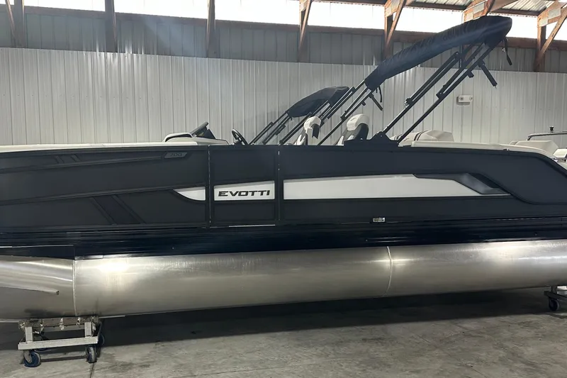 Slide: The Image of 2026 Evotti 723 CS pontoon boat in a warehouse, featuring sleek black and white design. - 0