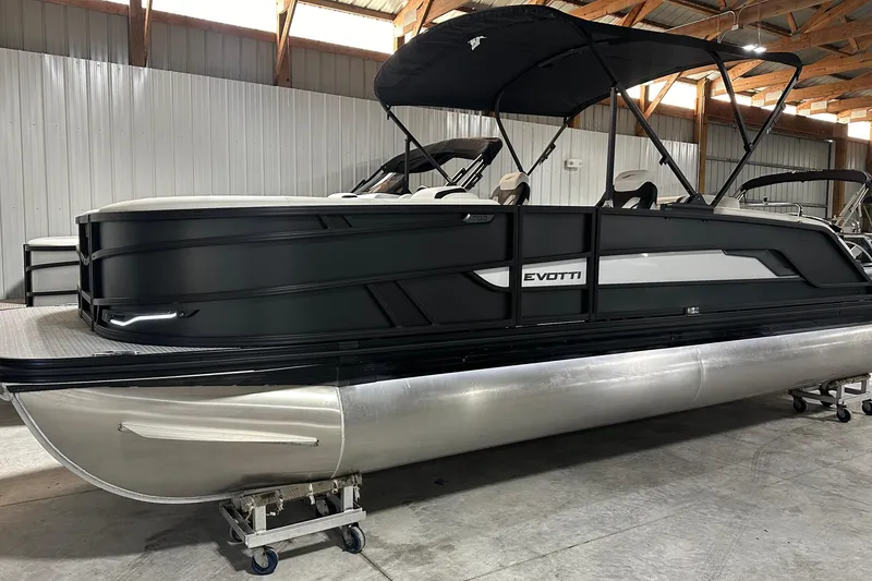 Slide: The Image of 2026 Evotti 723 CS pontoon boat in a warehouse, featuring sleek black and silver design. - 20