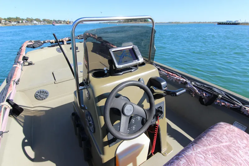 Slide: The Image of 2006 Xpress HD18CC boat interior with steering wheel and navigation system on calm water. - 18