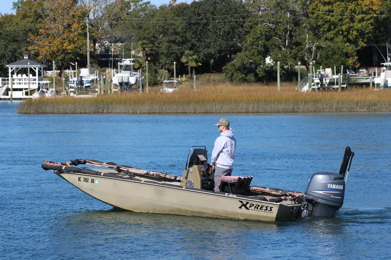 Slide: The Image of Man operating 2006 Xpress HD18CC boat on a calm river. - 2