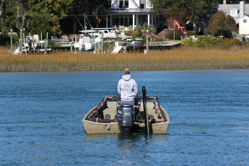 Slide: The Image of Man steering 2006 Xpress HD18CC boat on a calm river near a dock. - 5