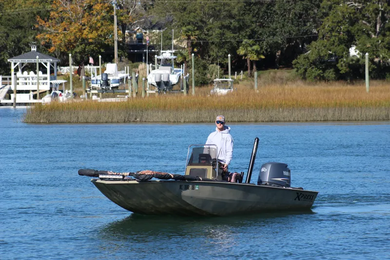 Slide: The Image of A person on a 2006 Xpress HD18CC boat in a calm waterway. - 9