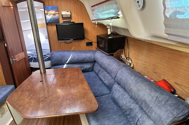 Slide: The Image of Interior of a 2000 Hunter 290 sailboat with blue seating and wooden table. - 10