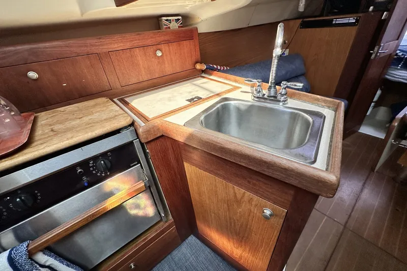 Slide: The Image of Compact kitchen area in a 2000 Hunter 290 sailboat with sink and oven. - 13