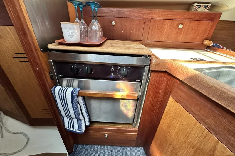 Slide: The Image of Galley kitchen in 2000 Hunter 290 sailboat with oven, sink, and wooden cabinetry. - 14