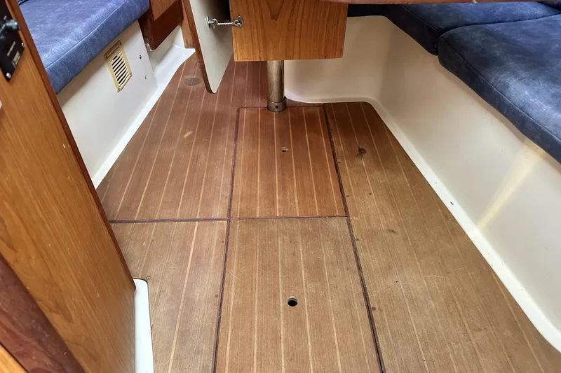 Slide: The Image of Interior of 2000 Hunter 290 sailboat with wooden flooring and blue cushioned seating. - 24