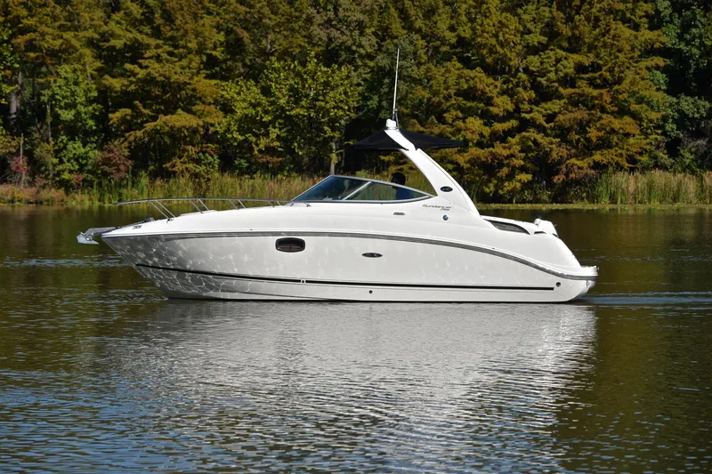 Slide: The Image of 2011 Sea Ray 260 Sundancer cruising on a calm lake with lush green trees. - 10