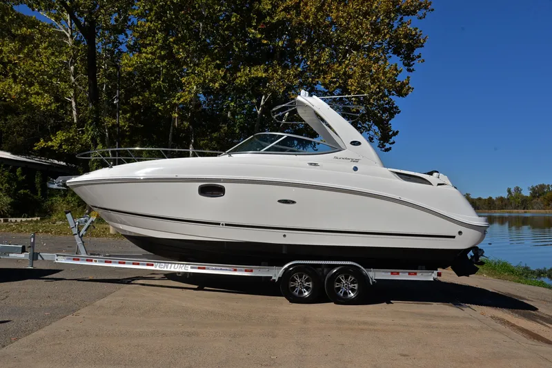 Slide: The Image of 2011 Sea Ray 260 Sundancer boat on trailer by a lake, surrounded by trees. - 12