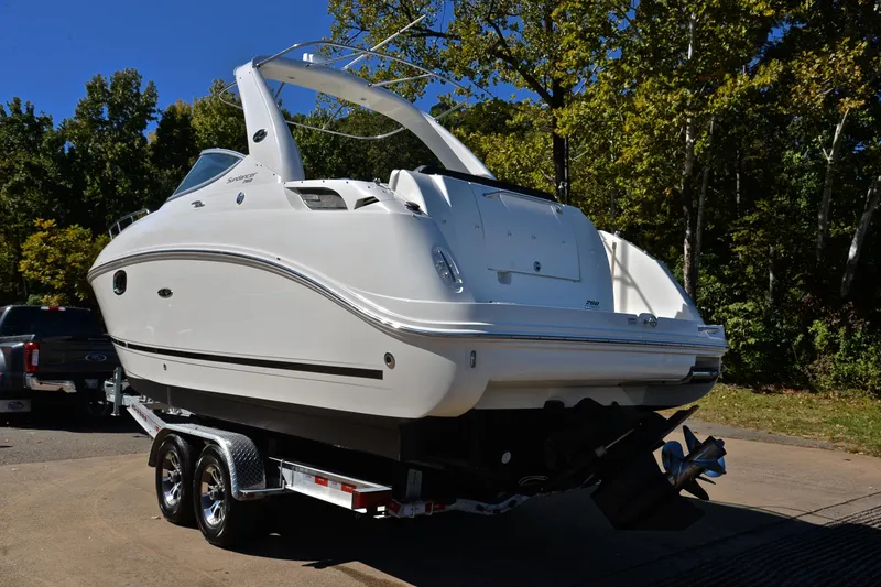 Slide: The Image of 2011 Sea Ray 260 Sundancer boat on trailer, parked outdoors with trees in background. - 13