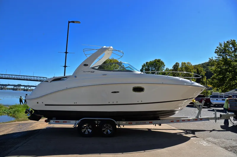 Slide: The Image of 2011 Sea Ray 260 Sundancer boat on trailer by riverside under clear blue sky. - 16