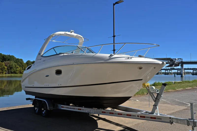 Slide: The Image of 2011 Sea Ray 260 Sundancer boat on trailer by a lake under clear blue sky. - 17