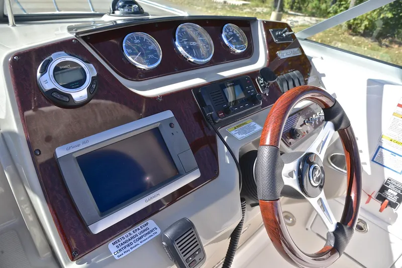 Slide: The Image of 2011 Sea Ray 260 Sundancer dashboard with GPS, gauges, and wood-trimmed steering wheel. - 28