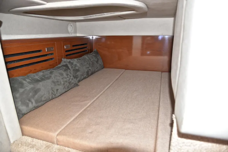 Slide: The Image of 2011 Sea Ray 260 Sundancer cabin interior with cushioned bed and wooden paneling. - 34