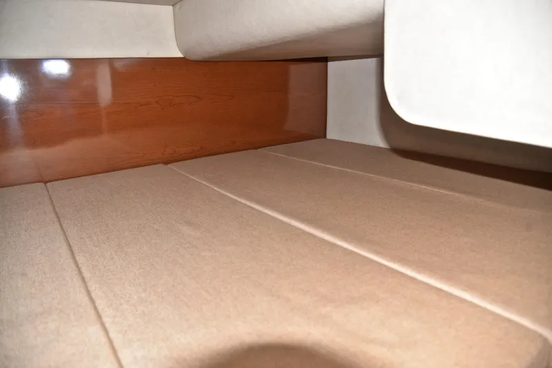 Slide: The Image of 2011 Sea Ray 260 Sundancer cabin interior with beige upholstery and wooden paneling. - 35