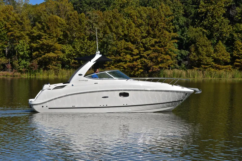 Slide: The Image of 2011 Sea Ray 260 Sundancer cruising on a serene lake with lush green trees. - 8
