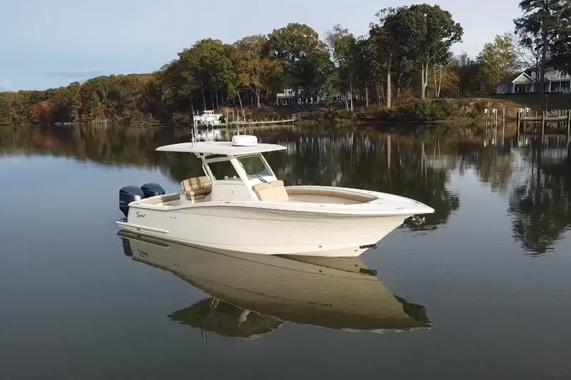 The Image of 2016 Scout 300 LXF boat on calm water with scenic forest backdrop. - 0