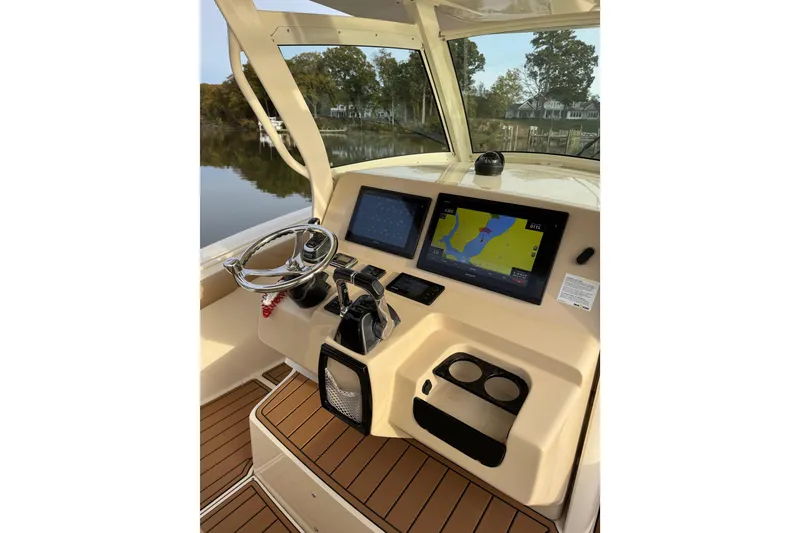 Slide: The Image of 2016 Scout 300 LXF boat interior with wood flooring, dashboard, and water view. - 19