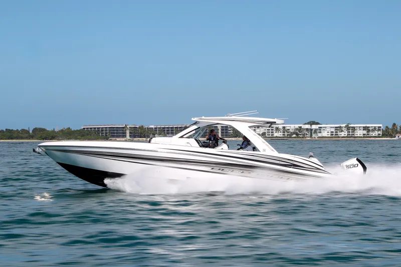 Slide: The Image of 2026 Deep Impact 449 Sport boat cruising near a lighthouse on a sunny day. - 2