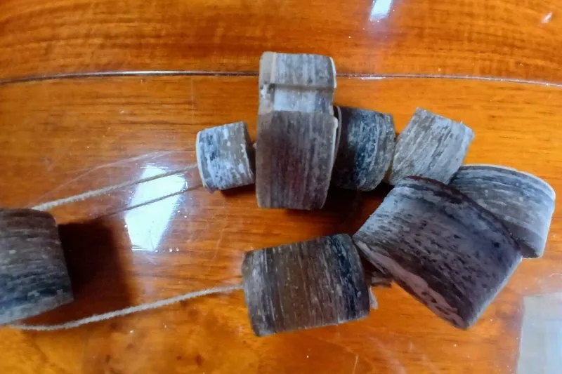 Slide: The Image of Wooden beads on string, displayed on a polished wooden surface. - 61