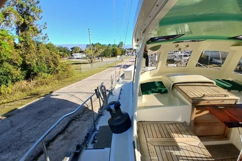 Slide: The Image of 1980 Hardin 45 sailboat deck with green canopy, docked near a tree-lined road. - 76