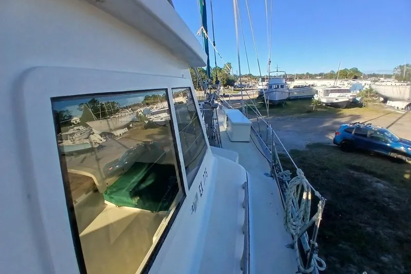 Slide: The Image of 1980 Hardin 45 sailboat docked, reflecting nearby boats and vehicles under clear blue sky. - 78
