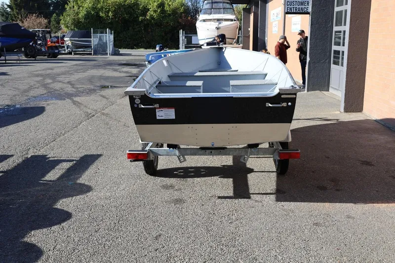 Slide: The Image of 2026 Lund SSV-16 Tiller boat on trailer outside dealership entrance. - 5