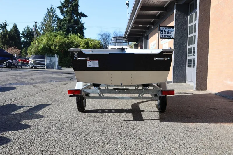 Slide: The Image of 2026 Lund SSV-16 Tiller boat on trailer, parked outside a building. - 6