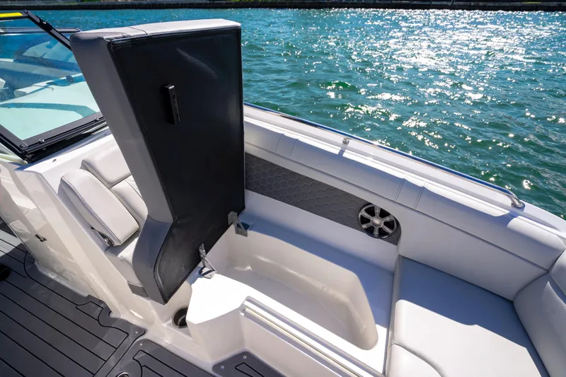 Slide: The Image of 2021 Yamaha AR250 boat interior with open storage compartment, gray seating, and water view. - 25