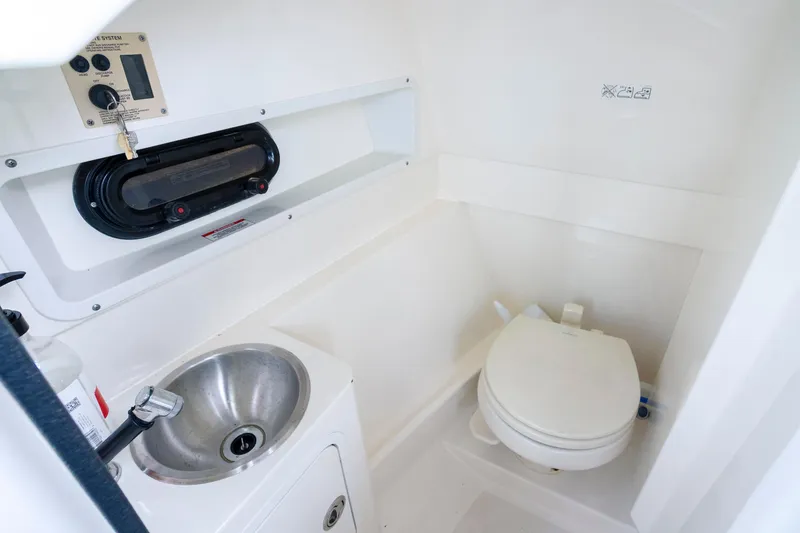 Slide: The Image of 2021 Yamaha AR250 boat interior with compact bathroom, featuring a sink and toilet. - 27