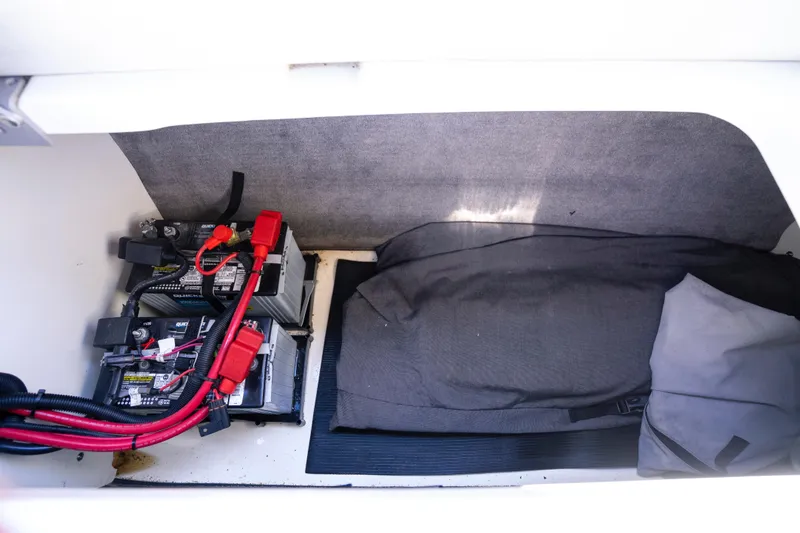 Slide: The Image of 2021 Yamaha AR250 boat battery compartment with cables and storage area. - 29