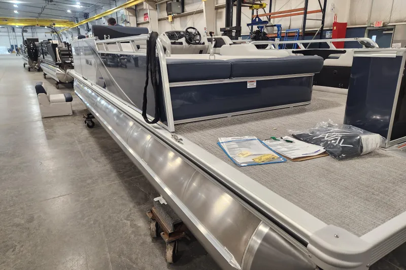 Slide: The Image of 2026 Avalon LSZ 2385 Entertainer pontoon boat with patio pad in a warehouse setting. - 16