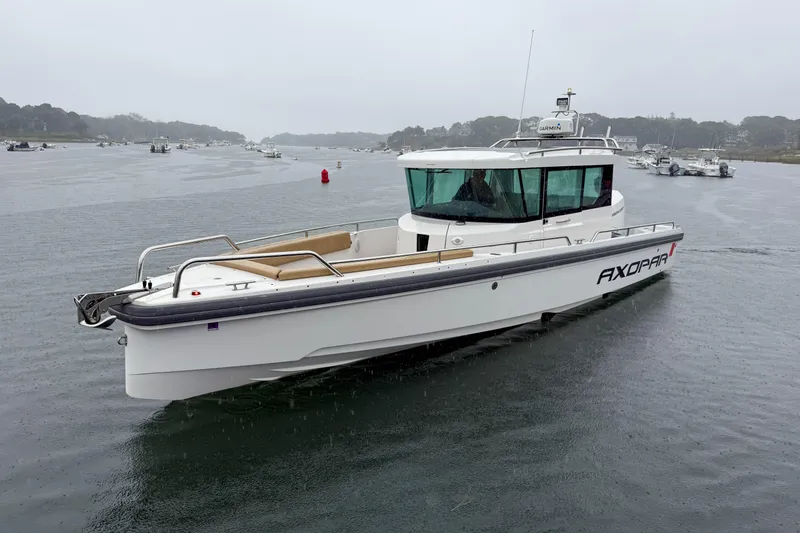 Slide: The Image of 2020 Axopar 28 Cabin with Wet Bar cruising on a calm, overcast waterway. - 2